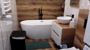 A modern bathroom with a freestanding bathtub, a sink, and a toilet. - Inviting 1-bed Apartment in Lebork (Lebork)
