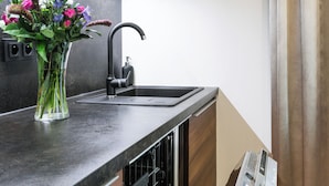 A modern kitchen with a built-in dishwasher, a black faucet, and a vase of flowers on the countertop. - Luxury Residence Kmochova (Prague)
