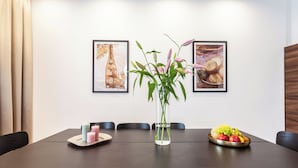 A dining table with chairs, a vase with flowers, and a fruit bowl. - Luxury Residence Kmochova (Prague)