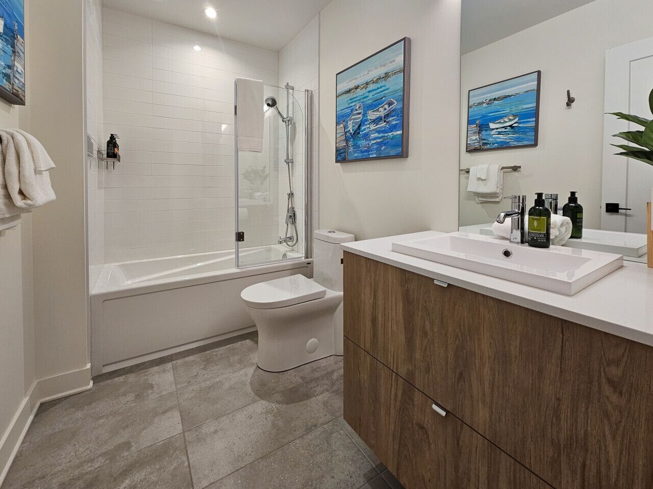 A modern bathroom with a glass-enclosed shower, a white toilet, and a wooden vanity with a sink.