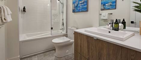 A modern bathroom with a glass-enclosed shower, a white toilet, and a wooden vanity with a sink.
