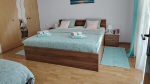 Un dormitorio con una cama de madera, dos mesitas de noche, un tocador, un cuadro en la pared y un armario.