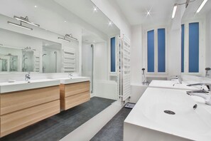Une salle de bain moderne avec deux lavabos, un grand miroir et une douche à l’italienne.