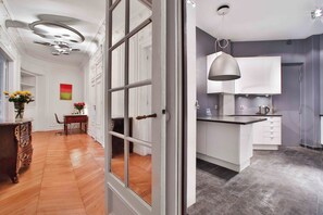 Une cuisine moderne avec des meubles blancs, un plan de travail gris et un luminaire suspendu.