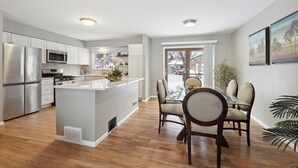 A modern kitchen with stainless steel appliances, a central island, and a dining area with a glass table and chairs. - Minne-getaway, Designer Stay South Of The River (Apple Valley)