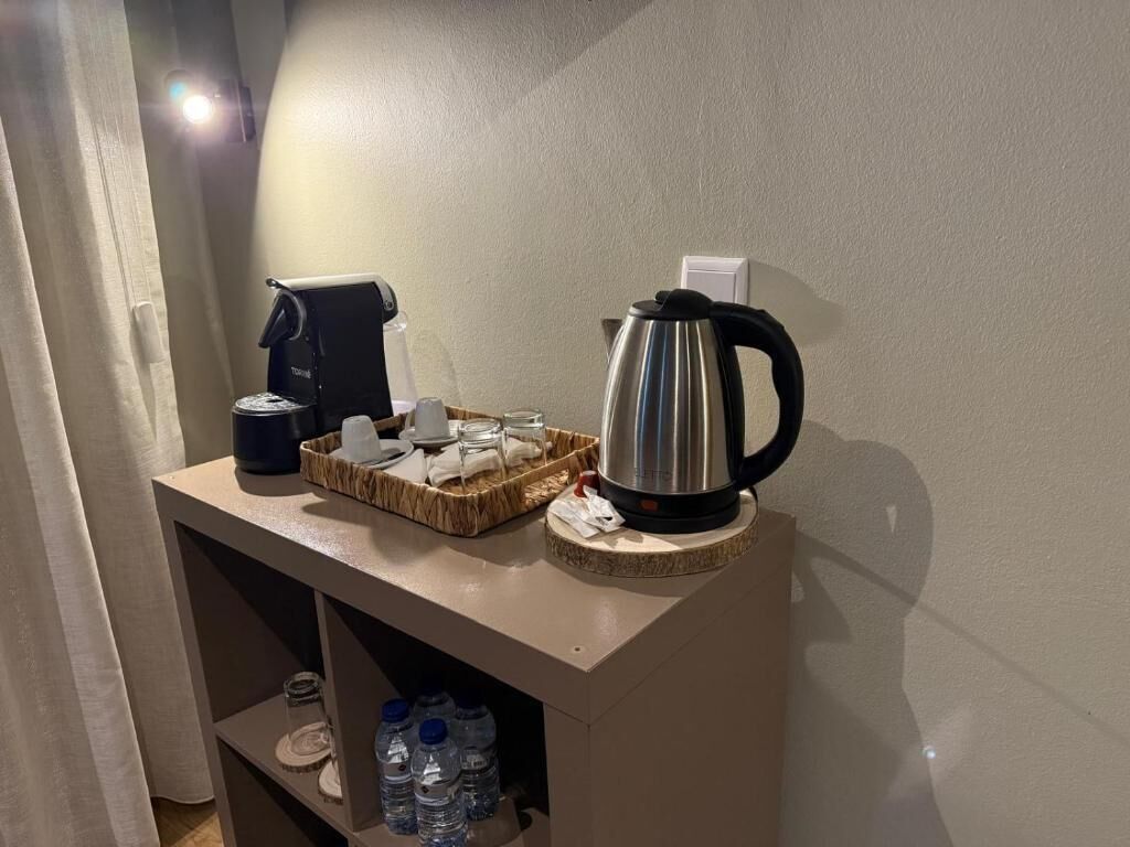 A kitchenette with a coffee maker, kettle, and water bottles on a counter.