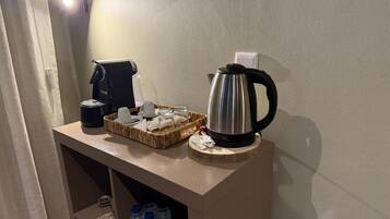 A kitchenette with a coffee maker, kettle, and water bottles on a counter.