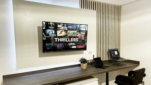 A modern office space with a large flat-screen TV displaying a selection of thriller movies. - Erin Court Mansion -Suite 11 (South Croydon)