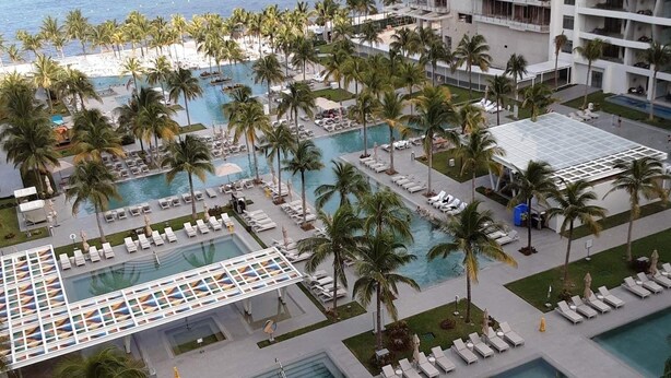 A resort with multiple swimming pools, palm trees, and a view of the ocean. - Christmas Heaven in Garza Blanca Mexico (Cancun)