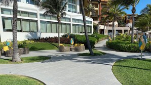 A modern hotel with a paved walkway, outdoor seating, and palm trees. - Christmas Heaven in Garza Blanca Mexico (Cancun)