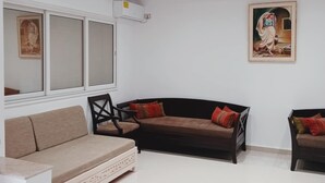 Un salon moderne avec un canapé, des fauteuils et un tableau accroché au mur.