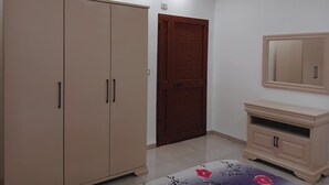 Une chambre à coucher avec une armoire, une porte, un miroir et un lit.