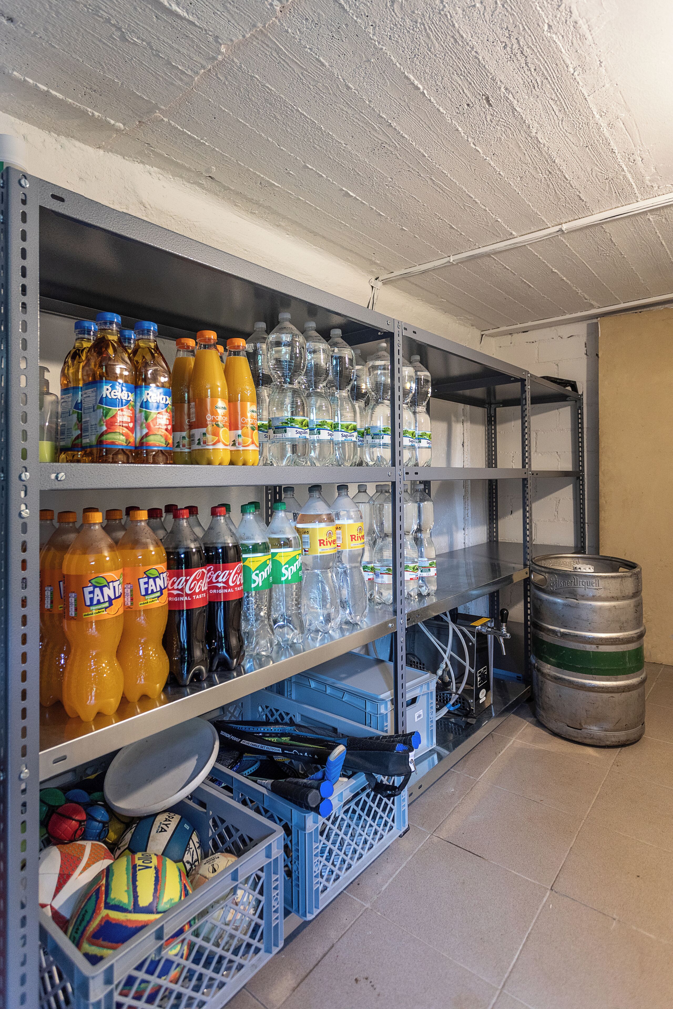 Une pièce de rangement dotée d’étagères remplies de boissons et d’articles de sport.