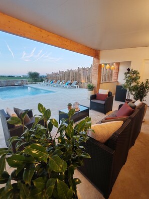 A poolside area with lounge chairs, a sofa, a coffee table, and a potted plant. - Domaine de Vizols (Garrigues)