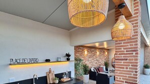 Une cuisine moderne avec un plan de travail noir, un îlot central en bois et des suspensions en osier.