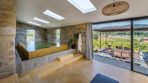 A modern spa room with a stone wall, a glass-enclosed hot tub, and a terrace with a view of vineyards. - Lemon Villa-indoor Pool (Porto)