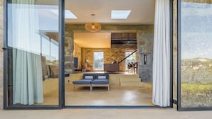 A modern interior with a stone wall, a sofa, a staircase, and a view of the outdoors. - Lemon Villa-indoor Pool (Porto)