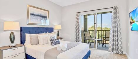 A bedroom with a large bed, two bedside tables, a painting, and a view of a balcony.