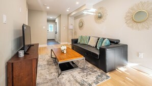 Ein modernes Wohnzimmer mit Couchtisch aus Holz, schwarzer Ledersofa und dekorativen Wandspiegeln.