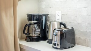 Eine Küchenzeile mit Kaffeemaschine, Toaster und Wasserkocher auf der Arbeitsfläche.
