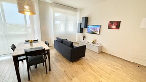 A modern living room with a dining table, sofa, and TV.
