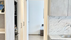 A modern kitchen with light wood flooring, white cabinetry, and a marble countertop.