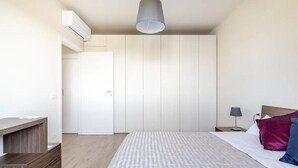 A bedroom with a bed, bedside table, lamp, and wardrobe.
