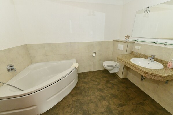 A bathroom with a bathtub, toilet, sink, and a large mirror.