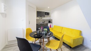 A compact living space with a dining area, a kitchenette, and a yellow sofa. -  GLM Residences 1 (Saint-Quentin)