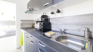 A modern kitchen with grey cabinets, a stainless steel sink, and a coffee machine. -  GLM Residences 1 (Saint-Quentin)