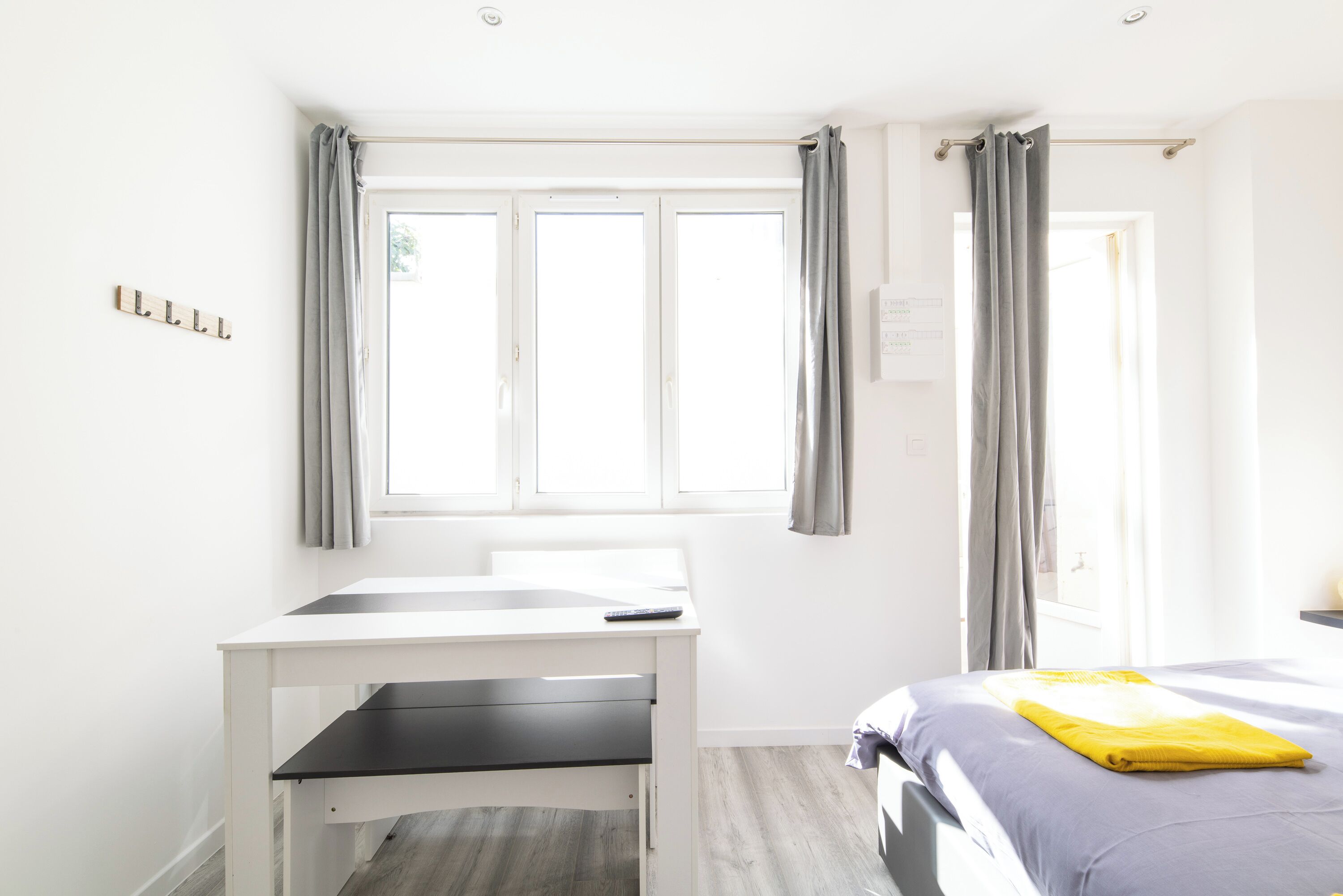 A bedroom with a bed, a desk, and a window with curtains.