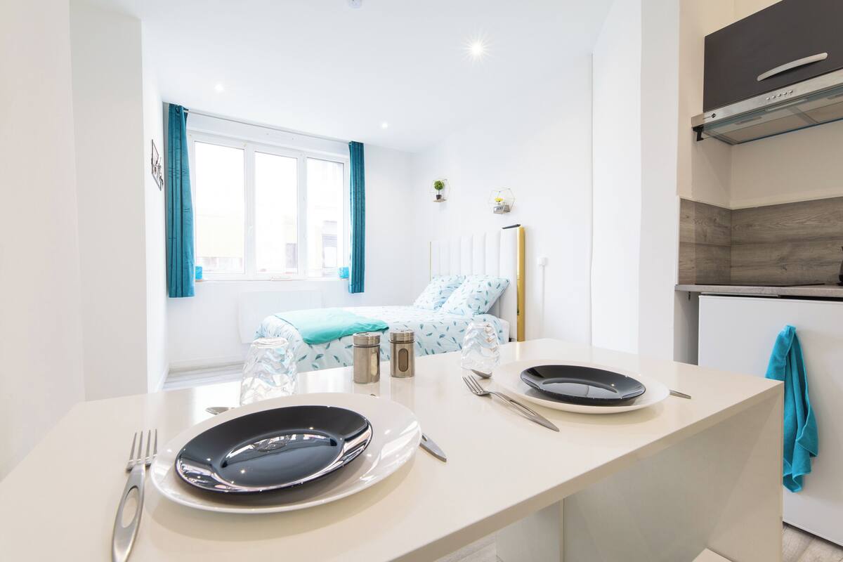 A modern kitchen with a dining area, a bed with a view, and a small kitchenette.