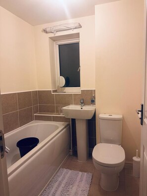 A compact bathroom with a bathtub, sink, and toilet.