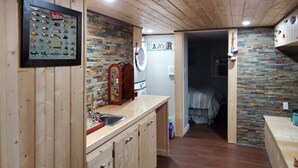A kitchen with wooden cabinets, a stone backsplash, and a framed fish lure collection. - William's Catch at Racoon Springs - 16+ Guests (Marshall)