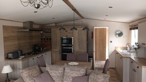 Una cocina moderna con armarios de madera, un comedor con cojines estampados y una araña.