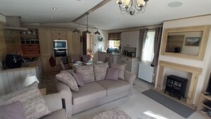 Una sala de estar acogedora con sofá, chimenea y una zona de cocina con armarios y televisor.