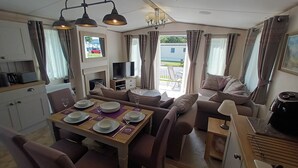 Un espacio habitable compacto con comedor, sofá, televisión y vistas al exterior.