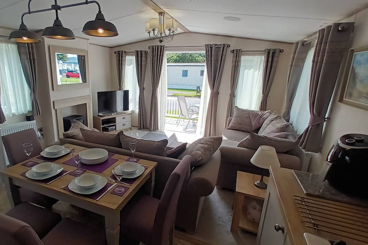Ein gemütlicher Wohnbereich mit Essplatz, Sofa, Fernseher und Blick ins Freie.