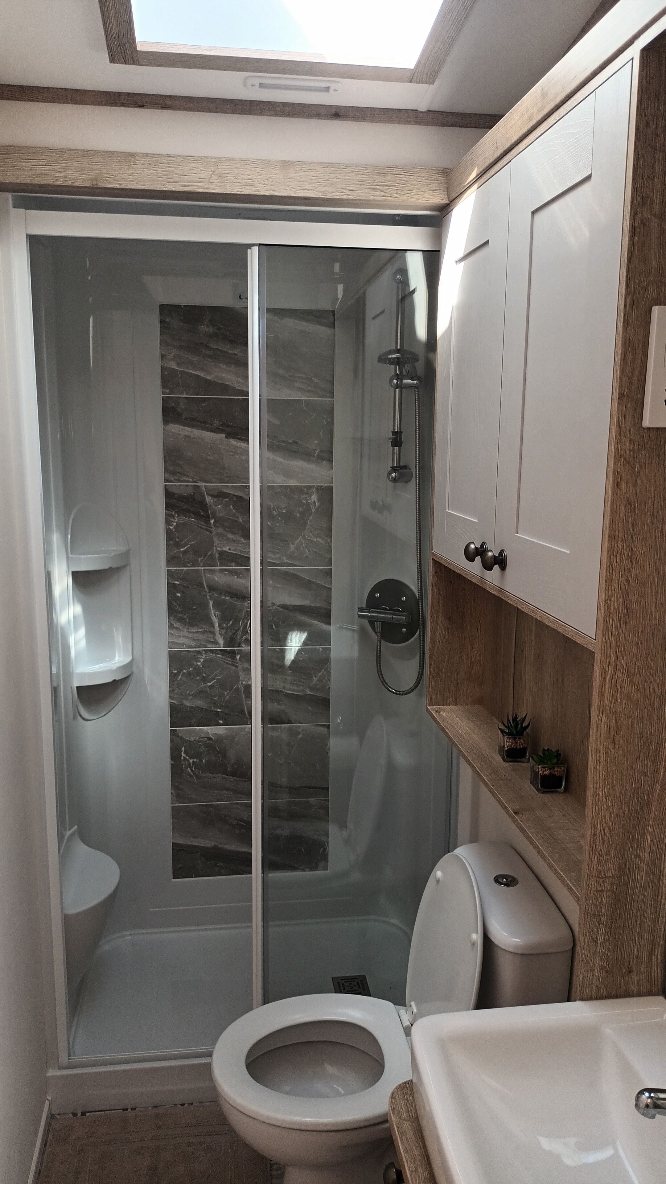 Un baño moderno con ducha de vidrio, inodoro y lavamanos.