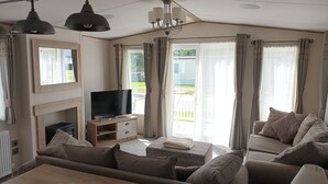 Una sala de estar con televisión, sofá, reposapiés y chimenea.