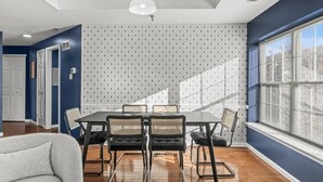 Un coin repas comprenant une table et des chaises, un luminaire au plafond et une fenêtre avec des stores.