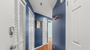 Un couloir aux murs bleus, aux portes blanches et au plancher en bois.