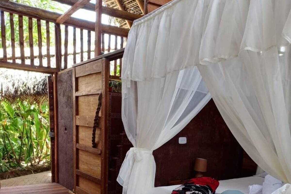 A wooden deck with a bed under a white canopy.