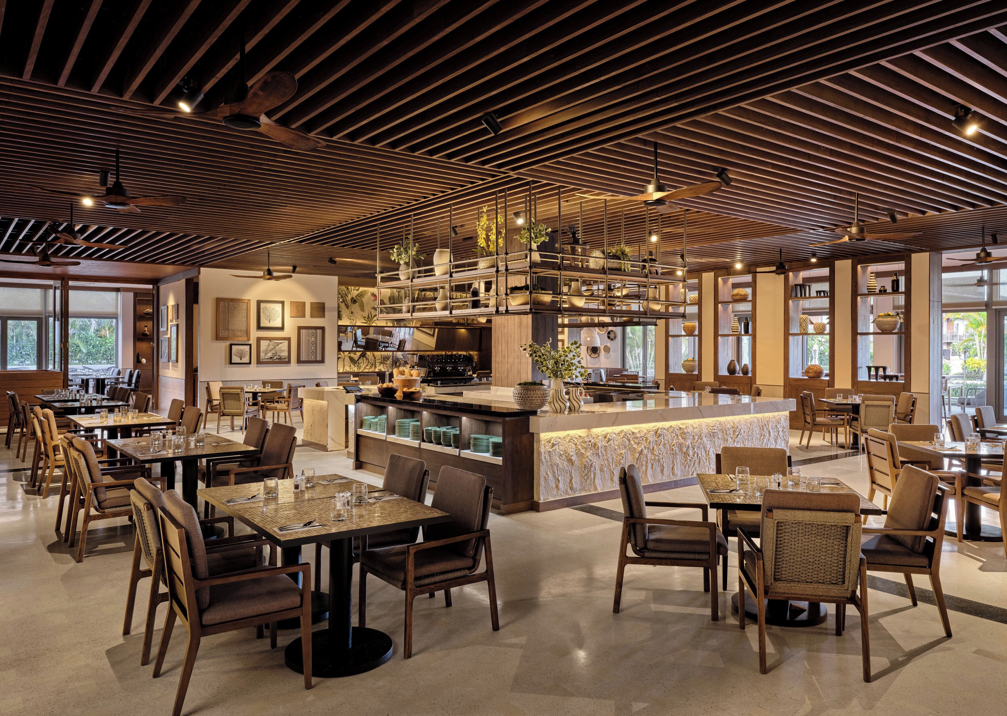 A spacious restaurant with high ceilings, wooden beams, and a central island with seating.