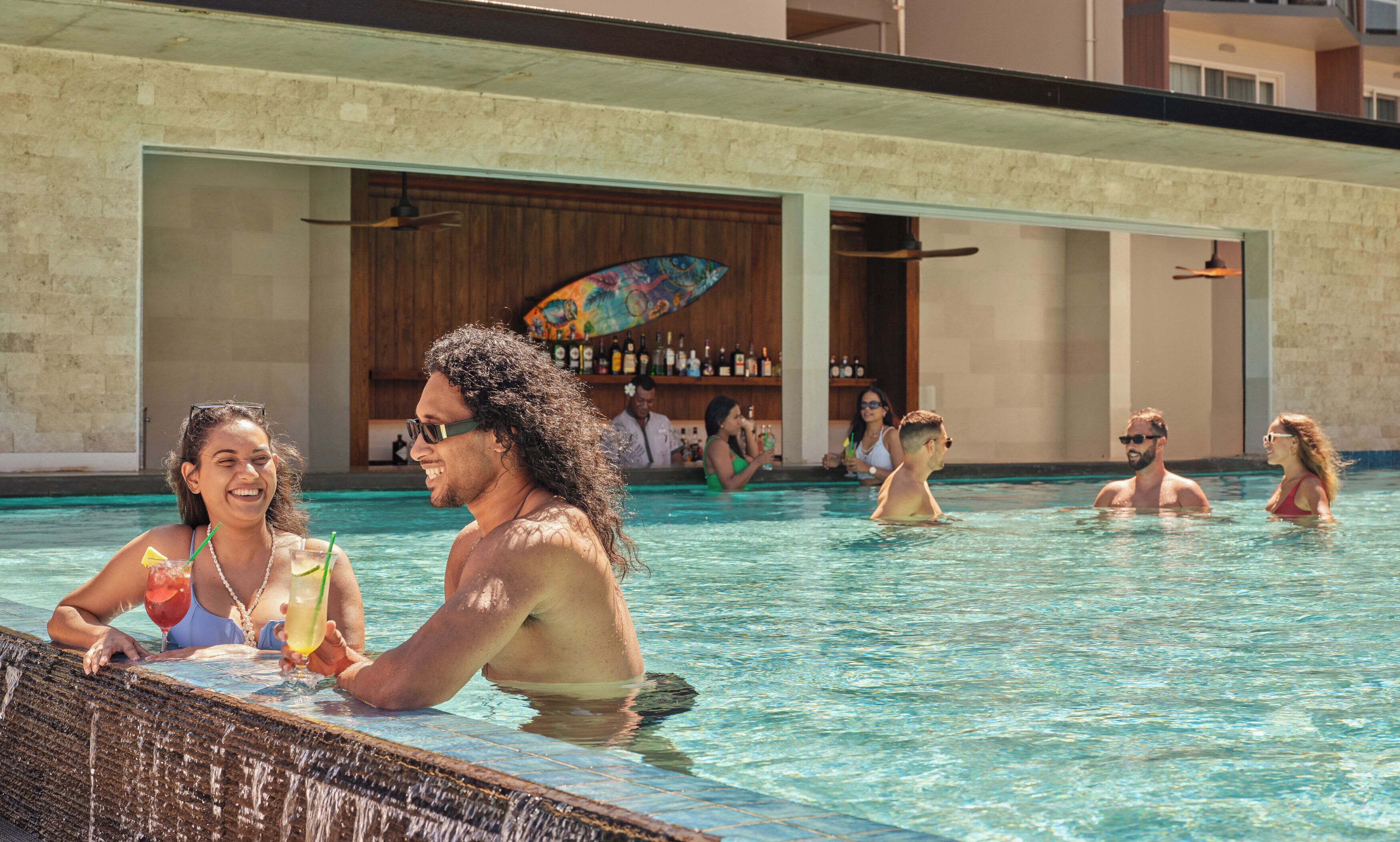 A pool area with clear water, a bar with bottles, and a wooden ceiling.