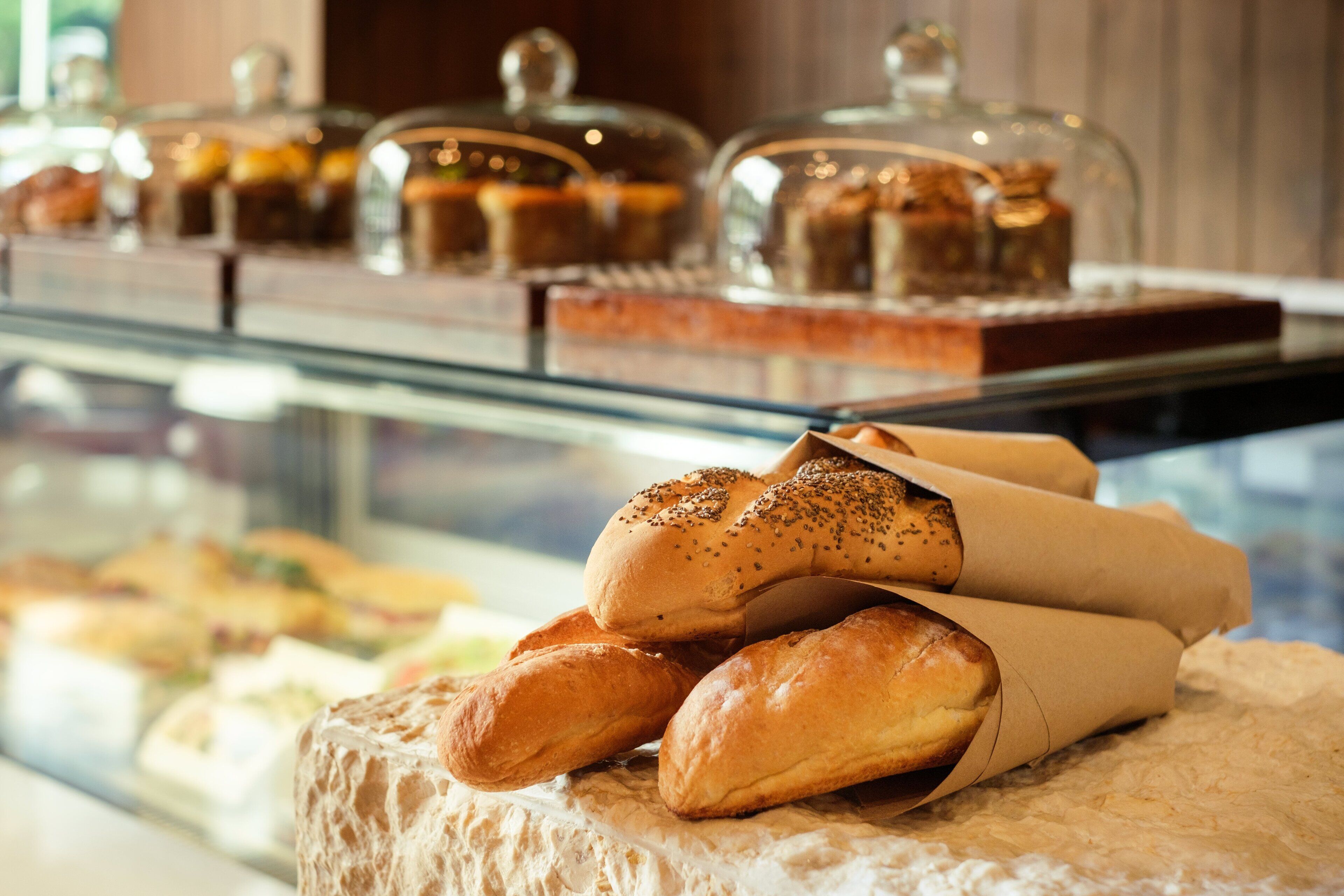 A display case with various baked goods and bread rolls.