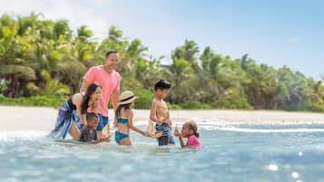 Una familia en una playa tropical, con palmeras y cielos despejados.