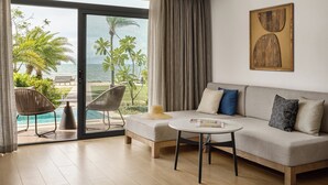 A modern living room with a sofa, a coffee table, and a view of a pool and palm trees. - Crowne Plaza Fiji Nadi Bay Resort & Spa by IHG (Nadi)