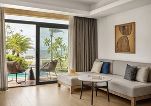 Una sala de estar moderna con un sofá, una mesa de centro y vistas a una piscina y palmeras.