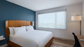 Ett modernt hotellrum med en säng i trä, ett skrivbord och ett stort fönster med utsikt.